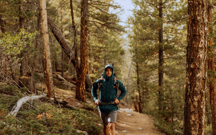 Junger Mann läuft mit Rucksack durch einen herbstlichen Wald